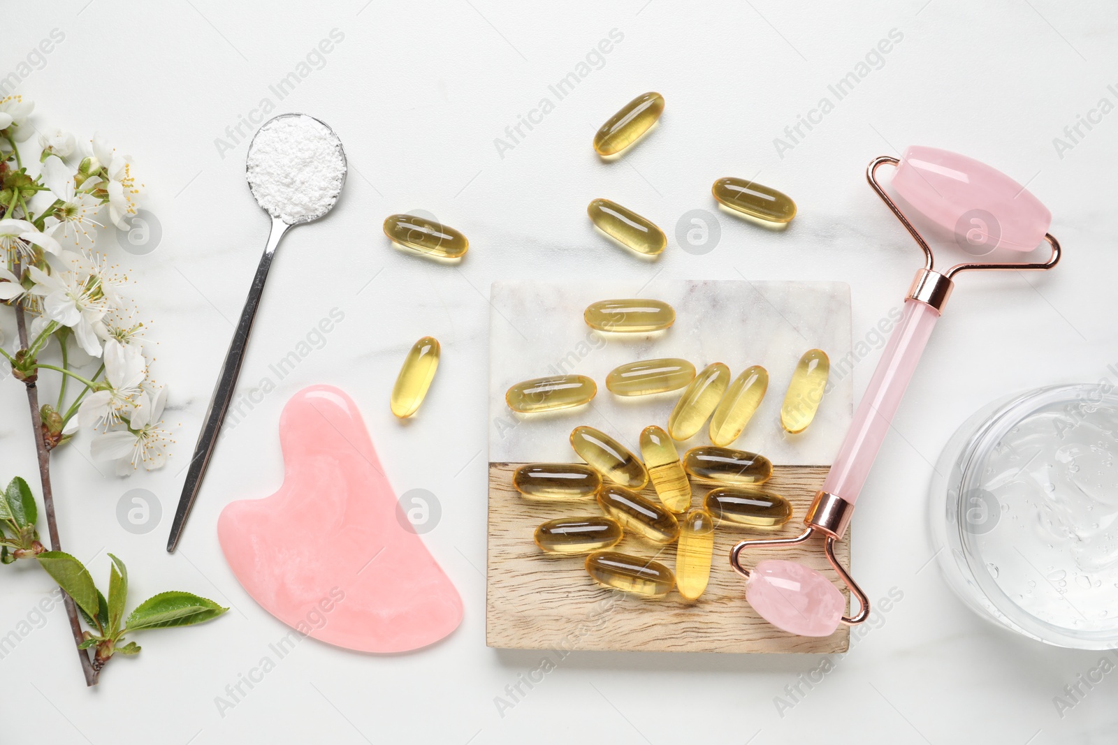 Flat lay composition with collagen capsules and blossoms on white marble table Photo of Flat lay composition with collagen capsules and blossoms on white marble table