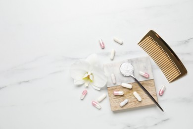 Photo of Collagen capsules, powder, comb and flower on white marble table, flat lay. Space for text