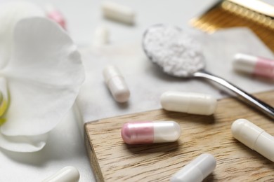 Photo of Collagen capsules, powder and flower on white table, closeup