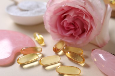 Photo of Collagen capsules and flower on beige background, closeup
