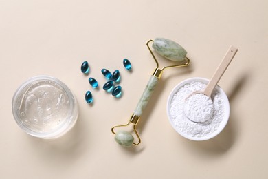 Photo of Collagen capsules, face roller, powder and gel on beige background, flat lay