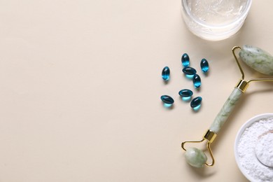 Photo of Collagen capsules, face roller, powder and gel on beige background, flat lay. Space for text