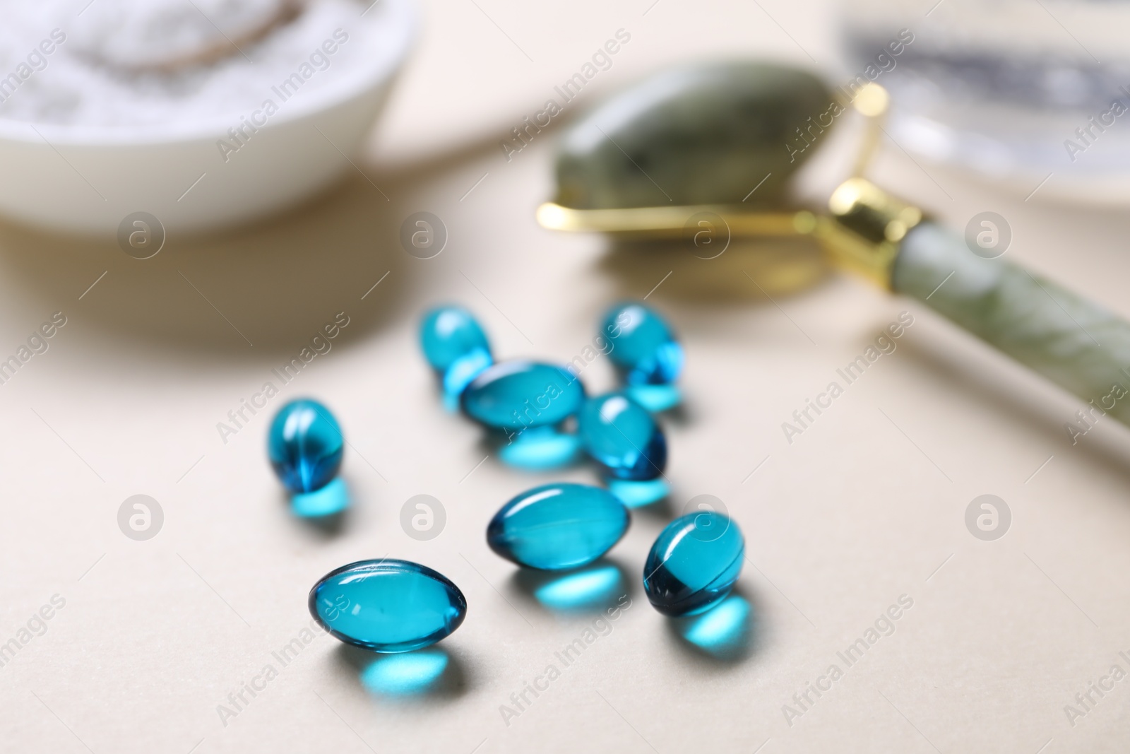 Collagen capsules, face roller and powder on beige background, closeup Photo of Collagen capsules, face roller and powder on beige background, closeup
