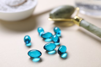 Photo of Collagen capsules, face roller and powder on beige background, closeup