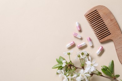 Photo of Collagen capsules, blossoms and comb on beige background, flat lay. Space for text