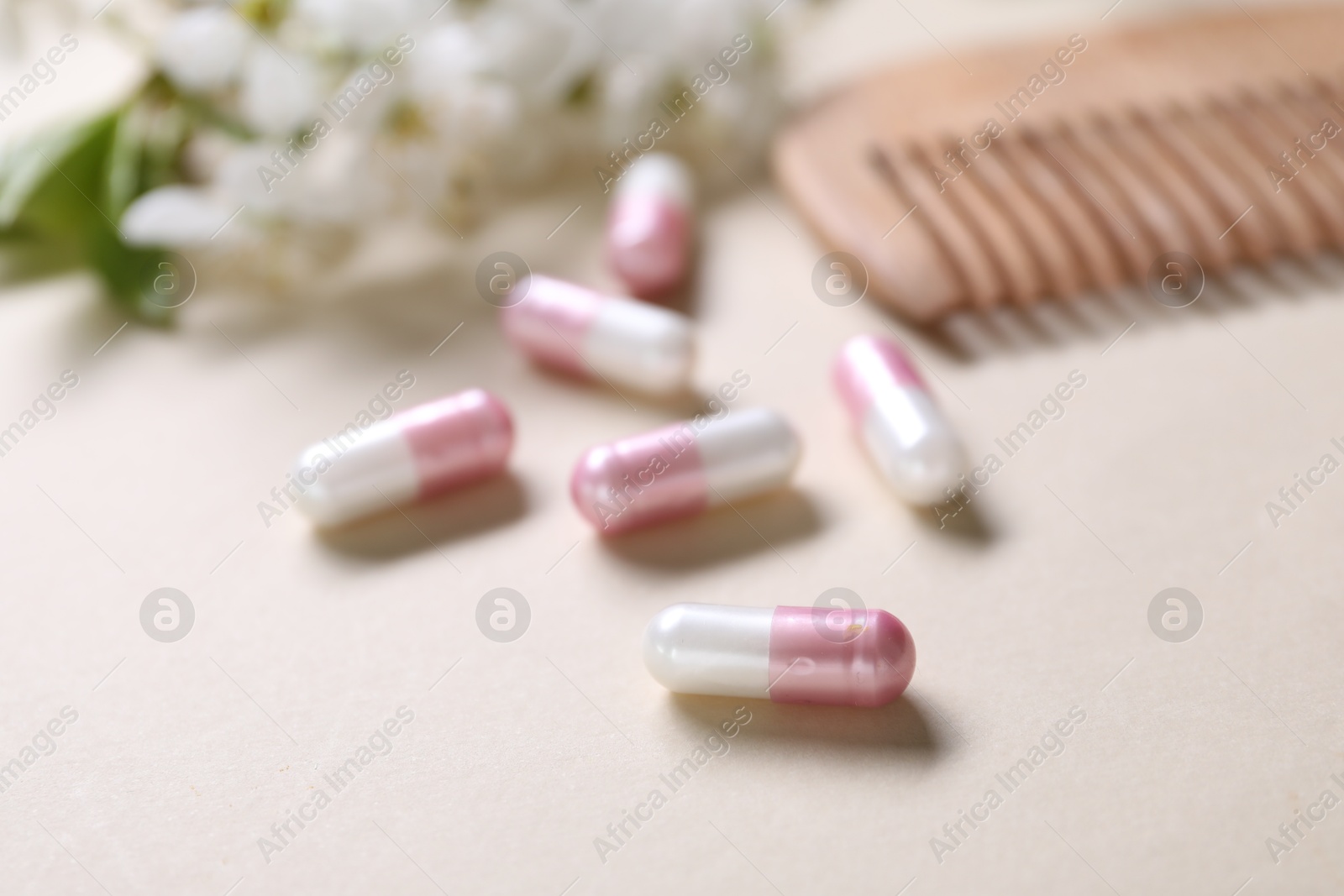 Collagen capsules, blossoms and comb on beige background, closeup Photo of Collagen capsules, blossoms and comb on beige background, closeup