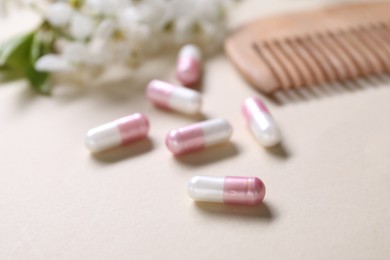 Photo of Collagen capsules, blossoms and comb on beige background, closeup