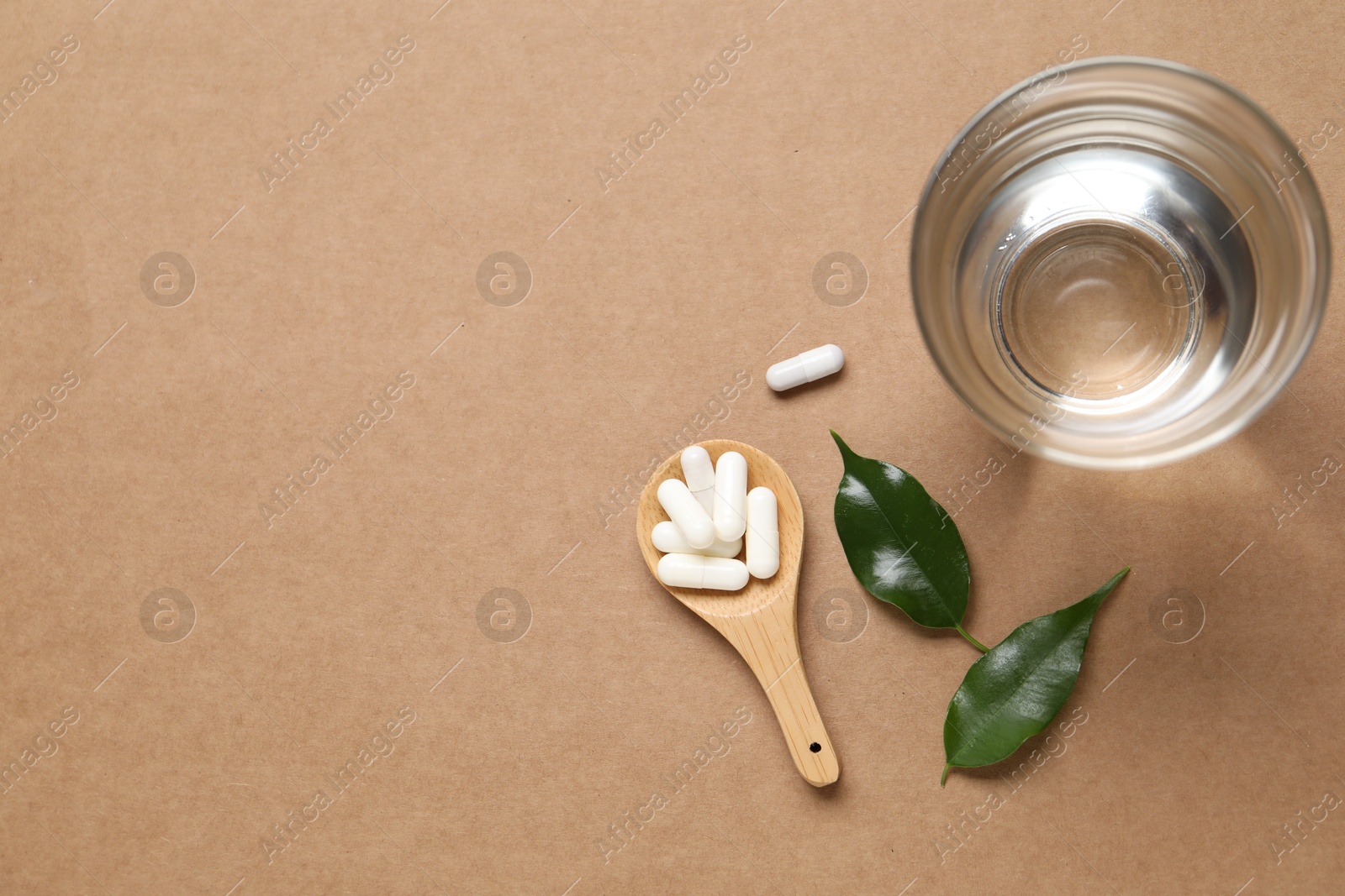 Collagen capsules, water and leaves on beige background, flat lay. Space for text Photo of Collagen capsules, water and leaves on beige background, flat lay. Space for text