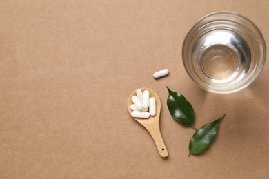 Photo of Collagen capsules, water and leaves on beige background, flat lay. Space for text
