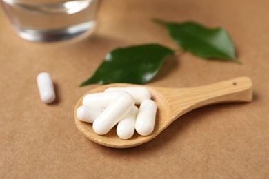Photo of Collagen capsules, water and leaves on beige background, closeup