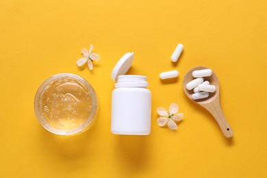 Photo of Collagen capsules, gel and flowers on orange background, flat lay