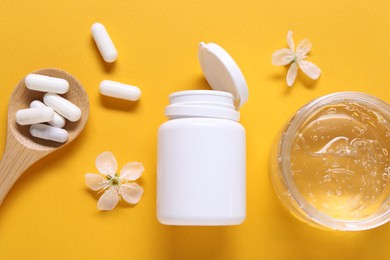 Photo of Collagen capsules, gel and flowers on orange background, flat lay