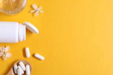 Photo of Collagen capsules, gel and flowers on orange background, flat lay. Space for text