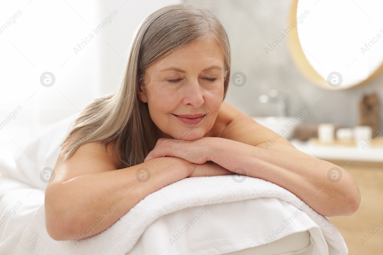 Senior woman relaxing on massage couch in spa salon Photo of Senior woman relaxing on massage couch in spa salon