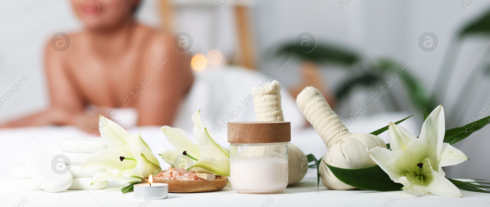 Beautiful woman relaxing on massage couch indoors, focus on different spa products and flowers Photo of Beautiful woman relaxing on massage couch indoors, focus on different spa products and flowers