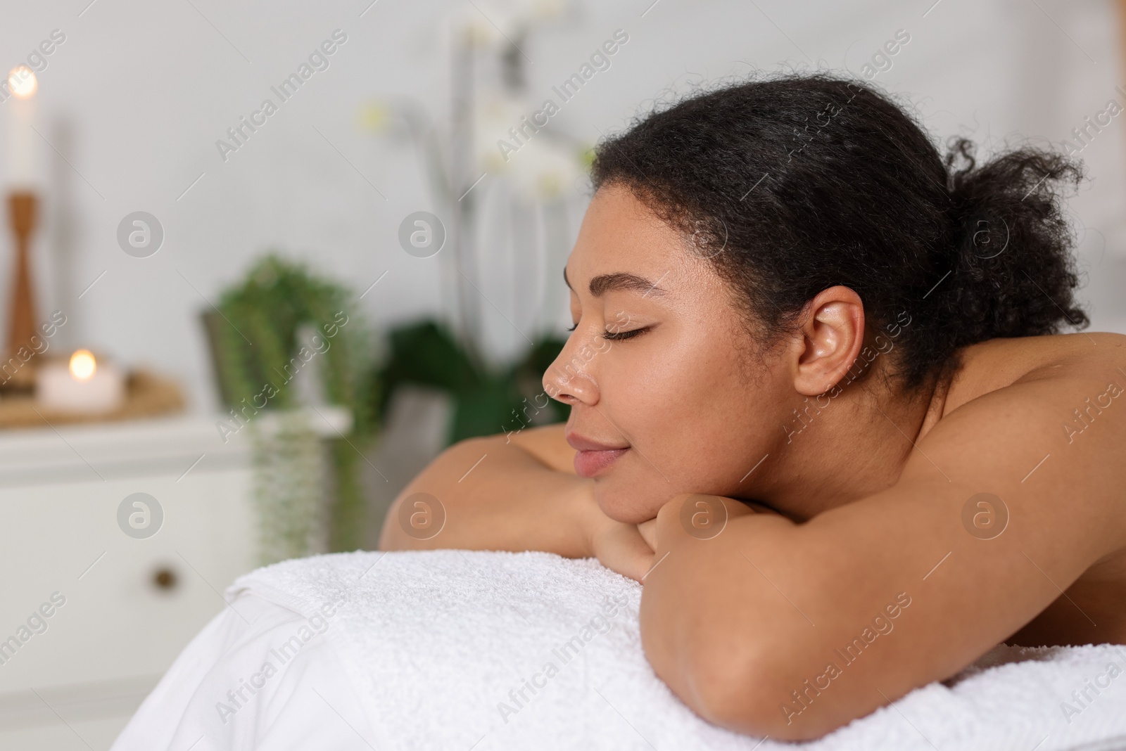 Beautiful woman relaxing on massage couch in spa salon, space for text Photo of Beautiful woman relaxing on massage couch in spa salon, space for text