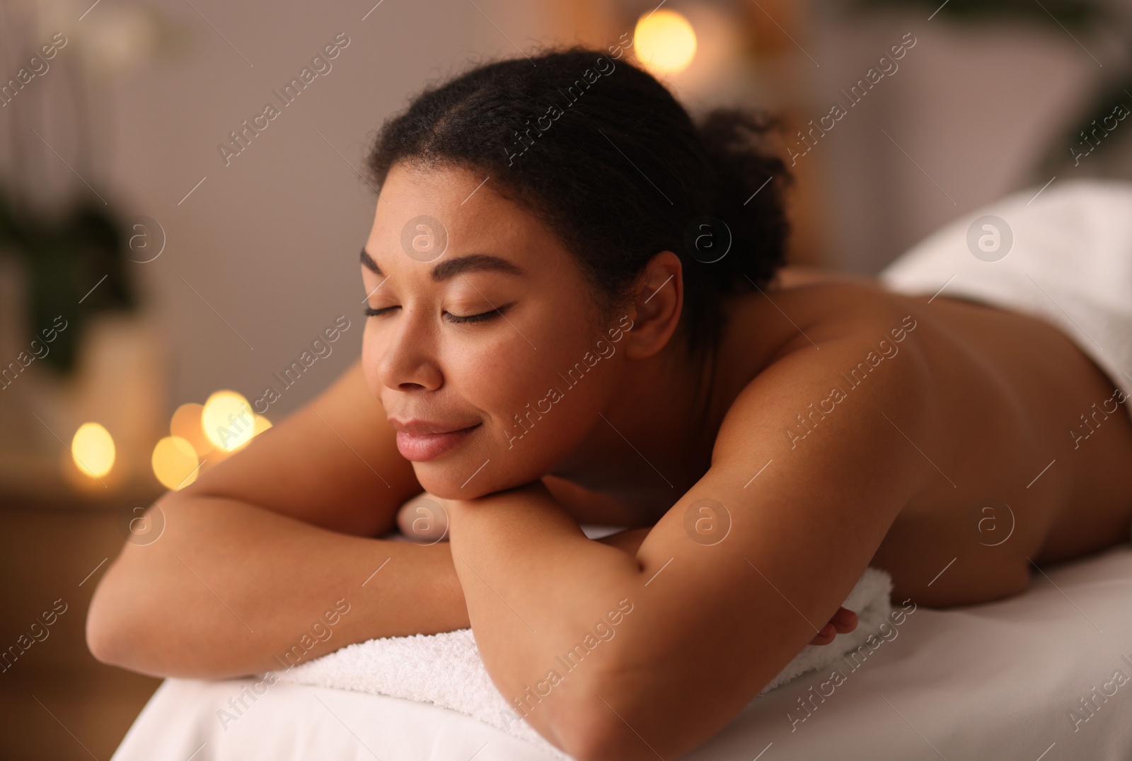 Photo of Beautiful woman relaxing on massage couch in spa salon