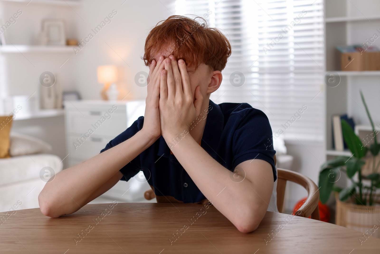 Teen problems. Depressed teenage boy at table indoors Photo of Teen problems. Depressed teenage boy at table indoors