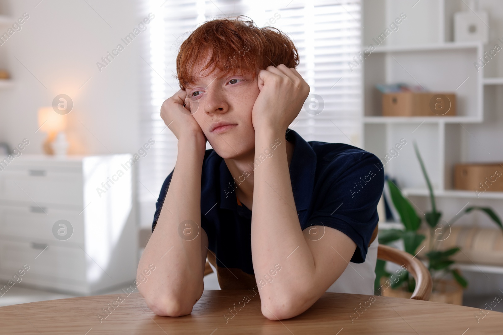 Teen problems. Depressed teenage boy at table indoors Photo of Teen problems. Depressed teenage boy at table indoors