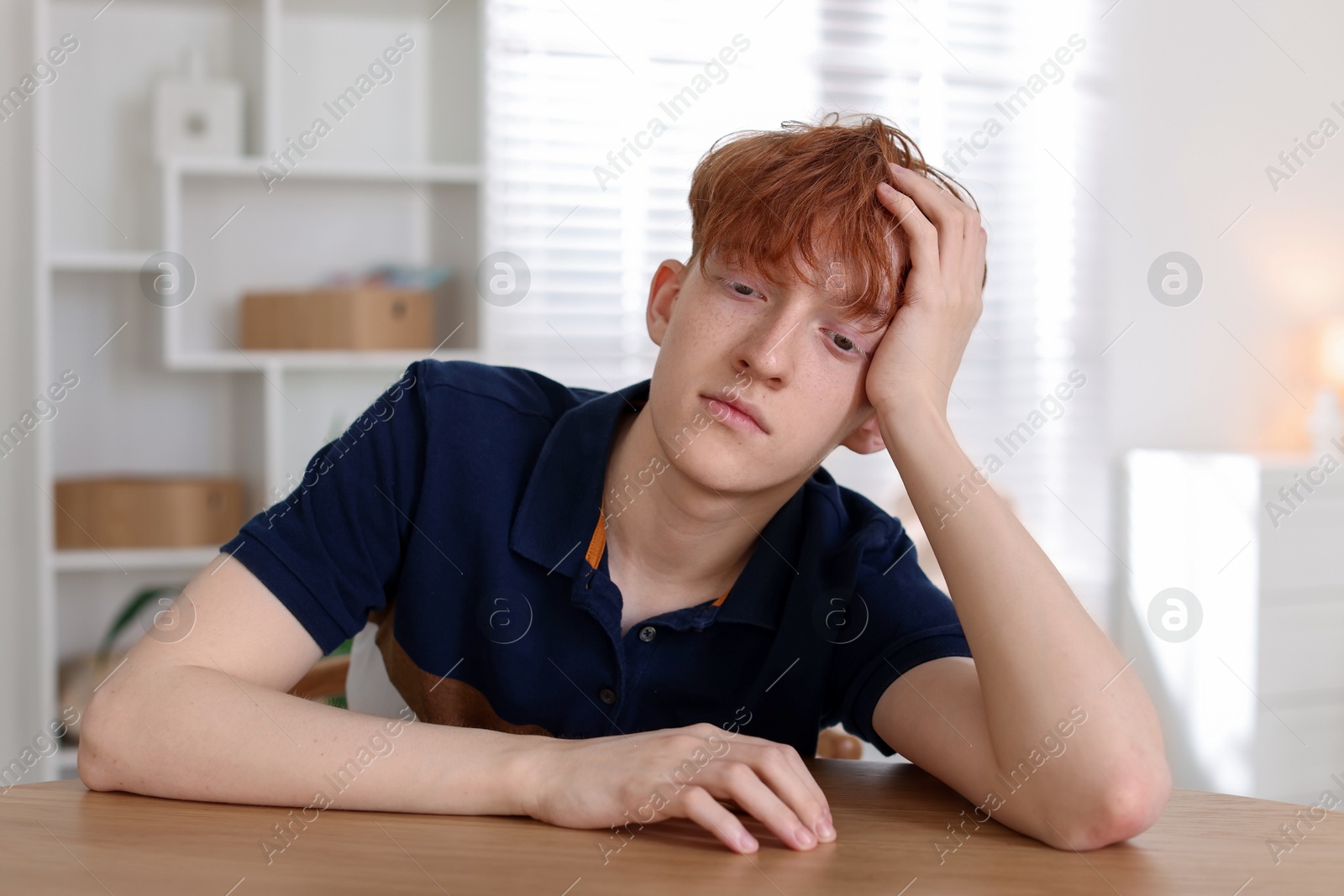 Teen problems. Depressed teenage boy at table indoors Photo of Teen problems. Depressed teenage boy at table indoors