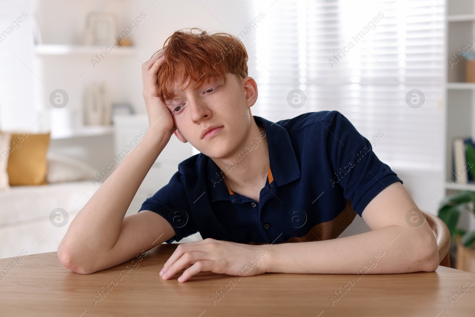 Teen problems. Depressed teenage boy at table indoors Photo of Teen problems. Depressed teenage boy at table indoors