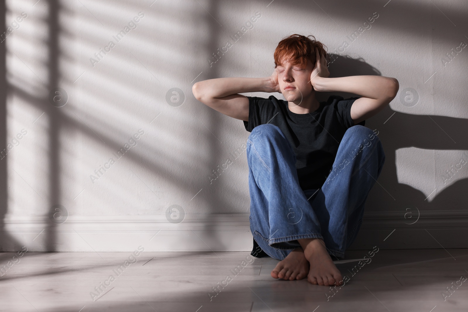 Teen problems. Depressed teenage boy on floor near grey wall, space for text Photo of Teen problems. Depressed teenage boy on floor near grey wall, space for text