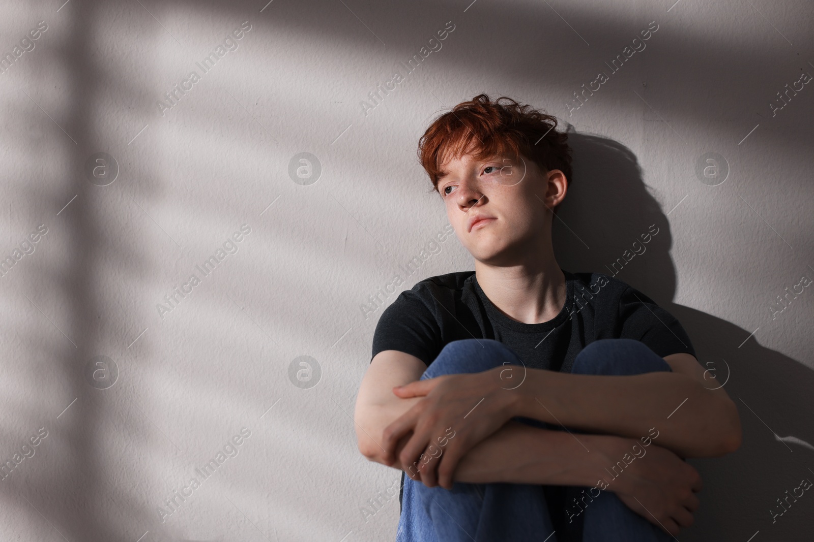 Teen problems. Depressed teenage boy near grey wall, space for text Photo of Teen problems. Depressed teenage boy near grey wall, space for text