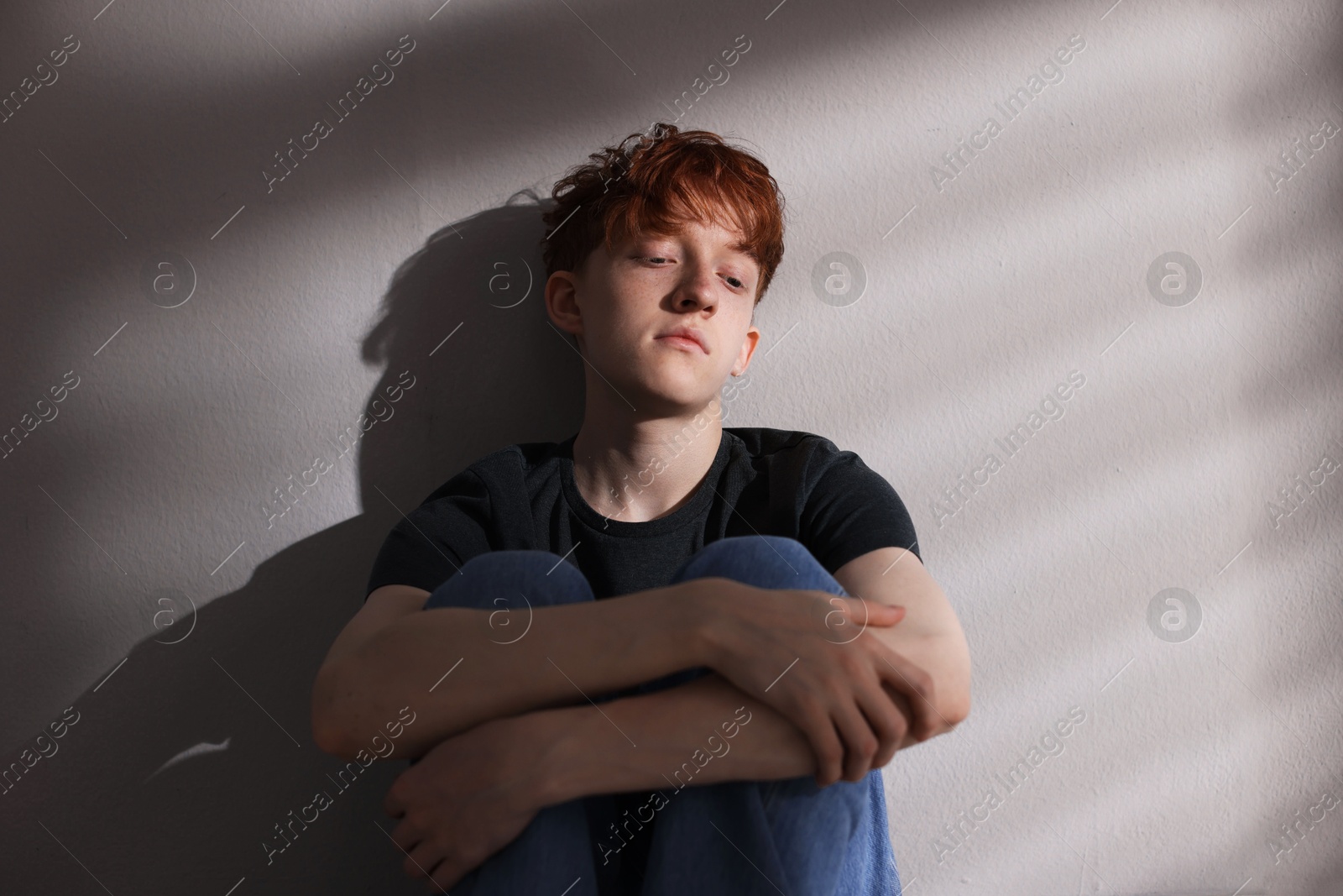 Teen problems. Depressed teenage boy near grey wall Photo of Teen problems. Depressed teenage boy near grey wall