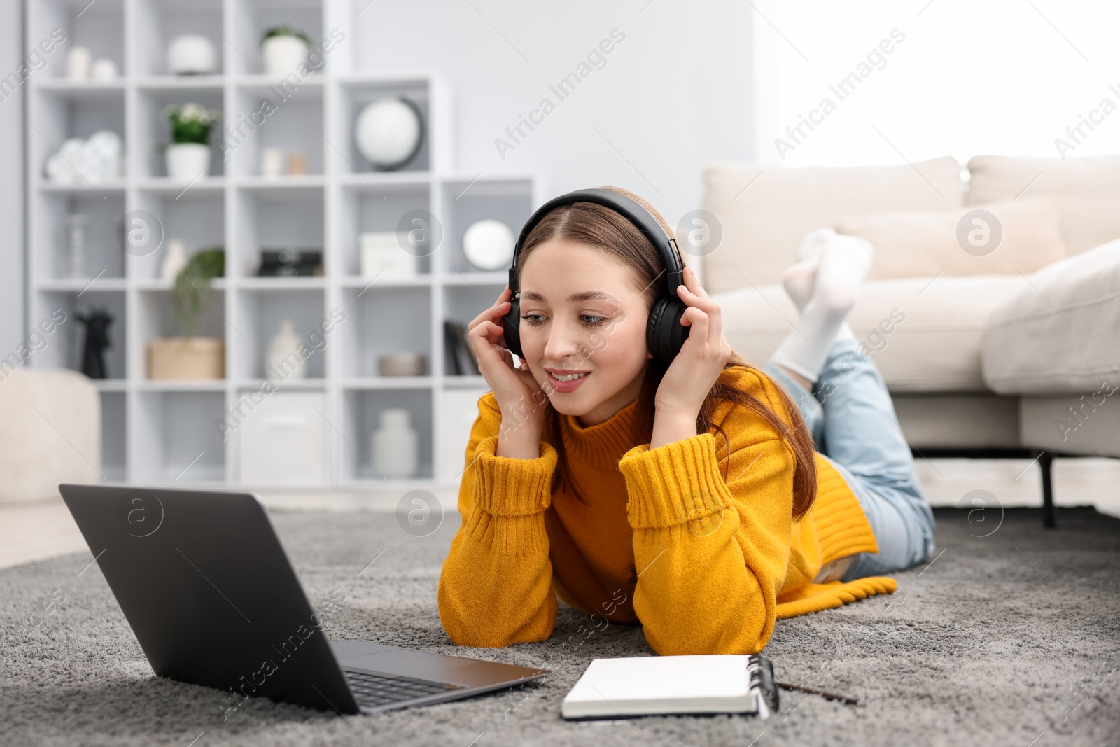 Photo of Teenage girl in headphones watching something on laptop at home