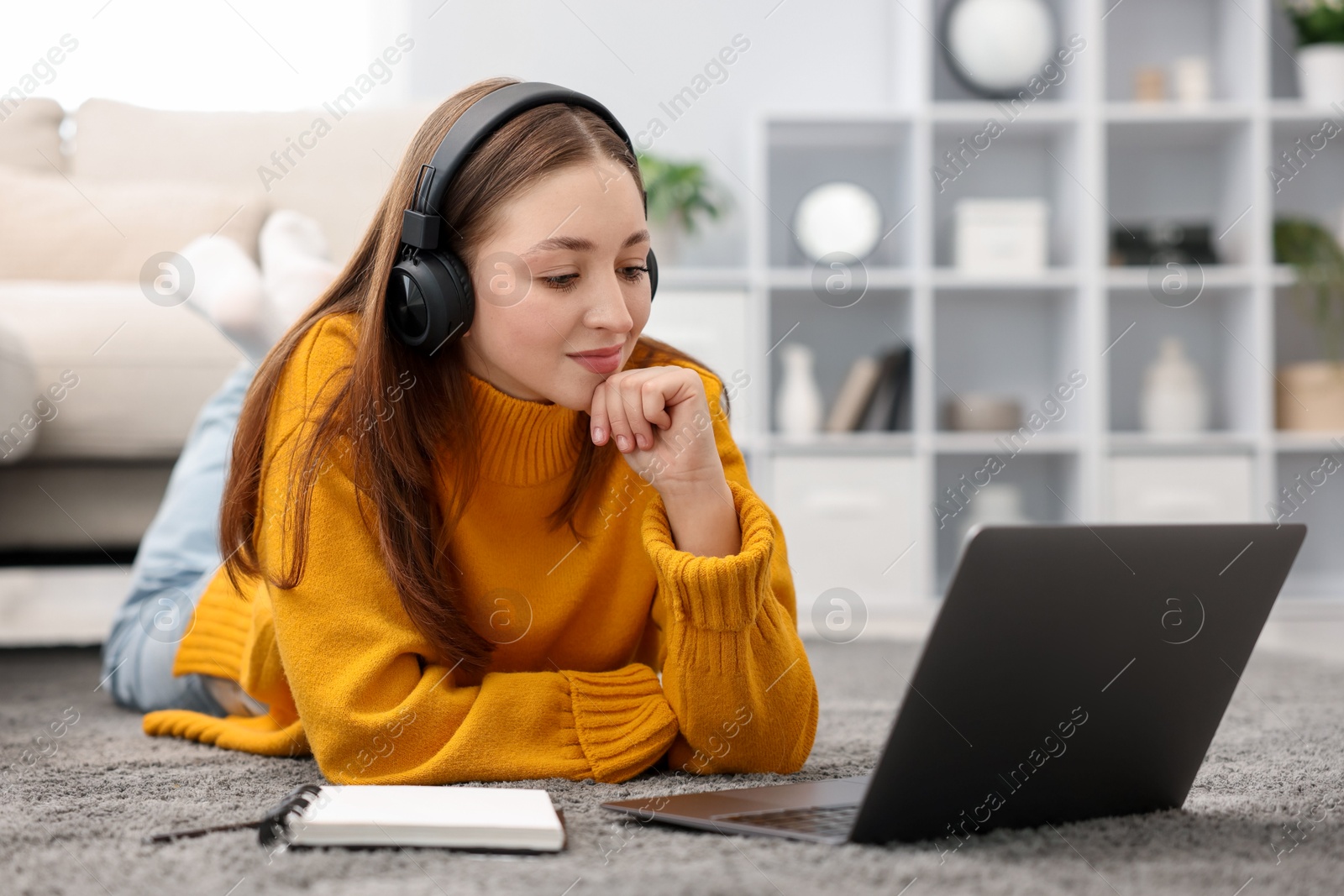 Teenage girl in headphones watching something on laptop at home Photo of Teenage girl in headphones watching something on laptop at home