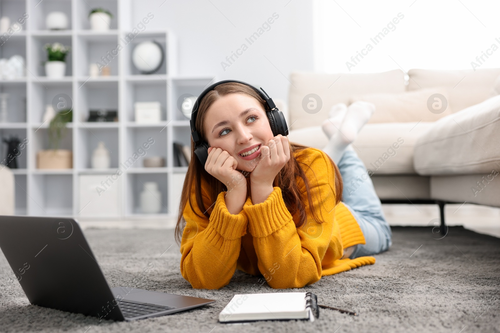 Photo of Teenage girl in headphones near laptop at home