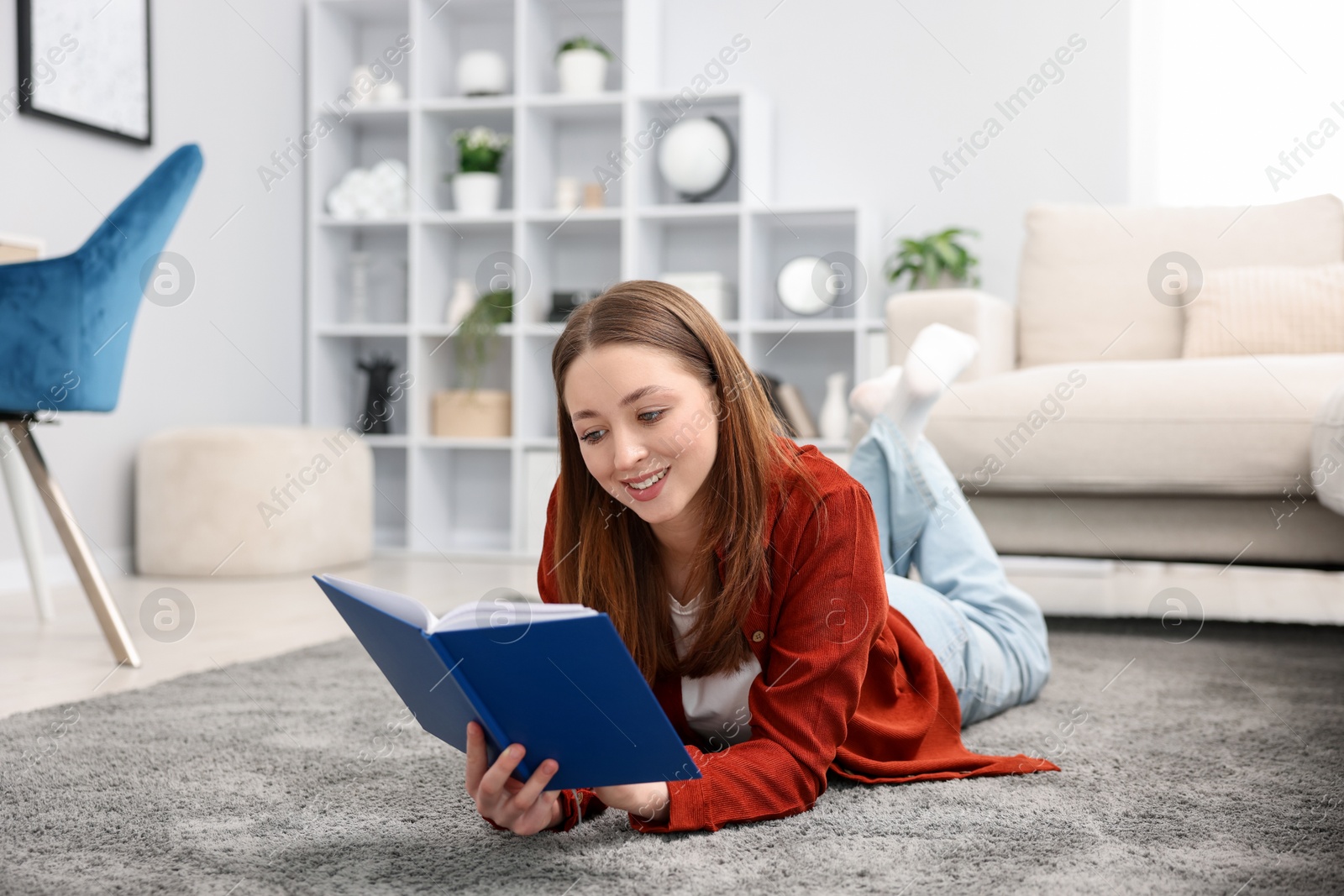 Teenage girl reading book on floor at home Photo of Teenage girl reading book on floor at home