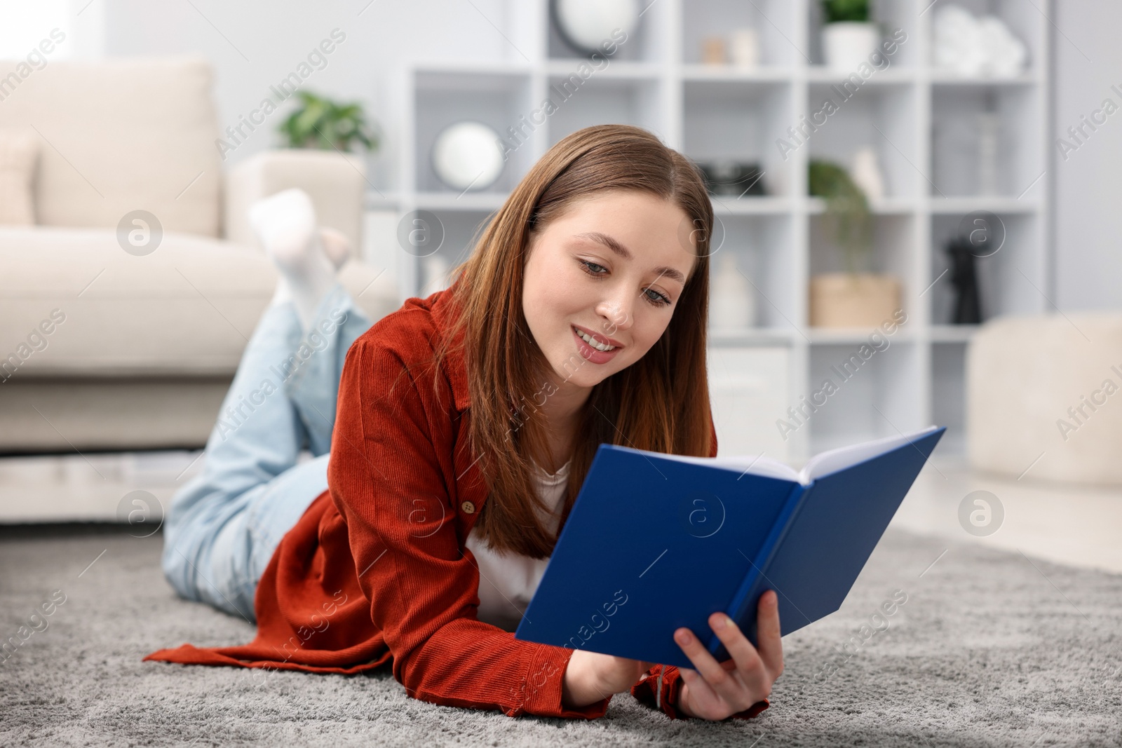 Teenage girl reading book on floor at home Photo of Teenage girl reading book on floor at home