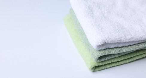 Photo of Stack of clean towels on white background, closeup. Space for text