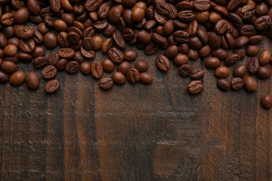 Photo of Aromatic coffee beans on wooden table, top view. Space for text