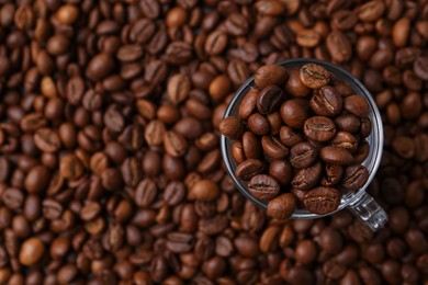 Photo of Aromatic coffee beans and glass cup on table, top view. Space for text