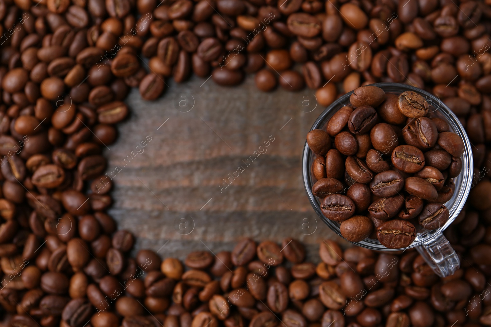 Aromatic coffee beans and glass cup on wooden table, flat lay. Space for text Photo of Aromatic coffee beans and glass cup on wooden table, flat lay. Space for text