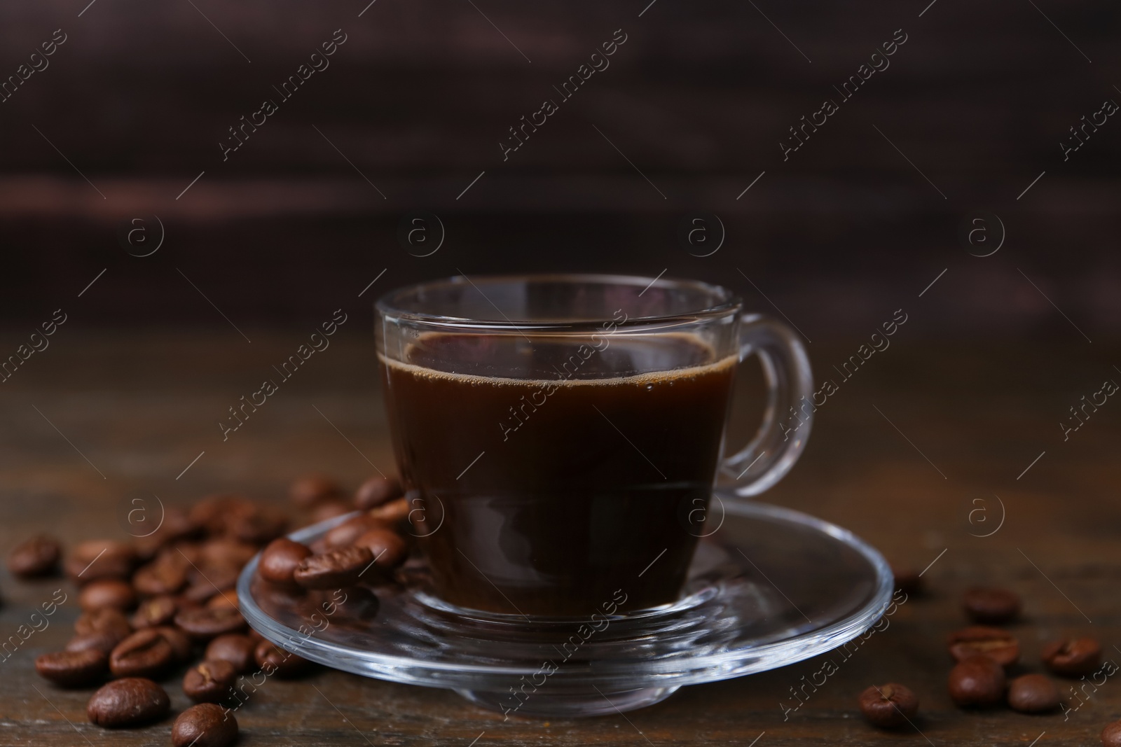 Aromatic coffee in glass cup and beans on wooden table, closeup Photo of Aromatic coffee in glass cup and beans on wooden table, closeup