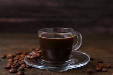 Photo of Aromatic coffee in glass cup and beans on wooden table, closeup