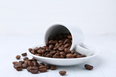 Photo of Aromatic coffee beans, cup and saucer on white table, closeup
