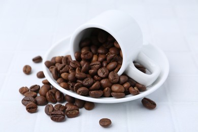 Photo of Aromatic coffee beans, cup and saucer on white table, closeup