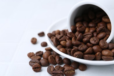 Photo of Aromatic coffee beans, cup and saucer on white table, closeup. Space for text