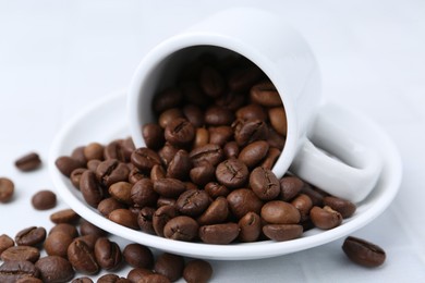 Photo of Aromatic coffee beans, cup and saucer on white table, closeup
