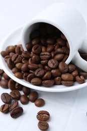 Photo of Aromatic coffee beans, cup and saucer on white table, closeup