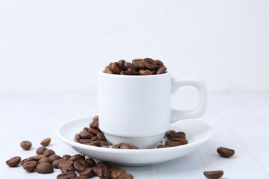 Photo of Aromatic coffee beans, cup and saucer on white table, closeup