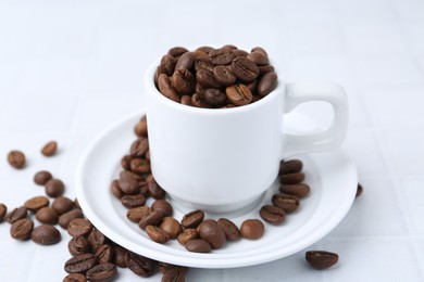 Photo of Aromatic coffee beans, cup and saucer on white table, closeup