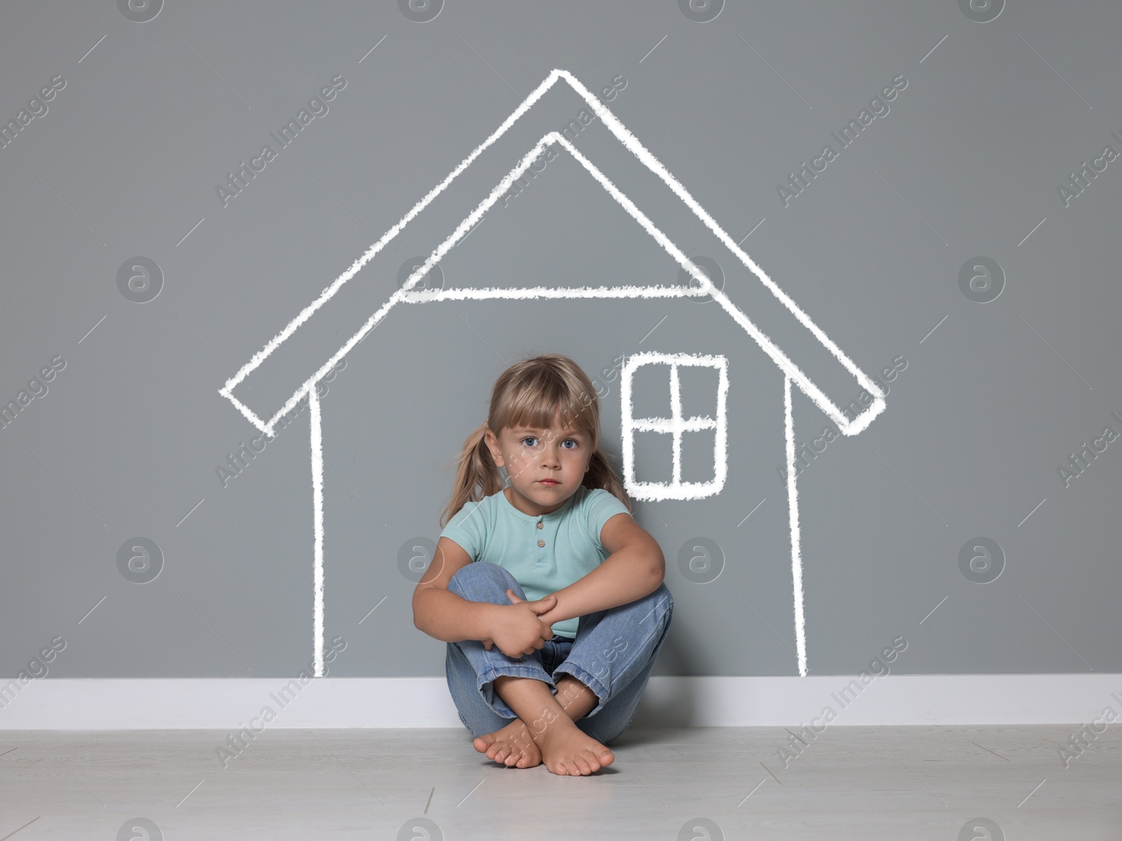 Orphanage. Sad little girl on floor near grey wall with drawing of house Image of Orphanage. Sad little girl on floor near grey wall with drawing of house