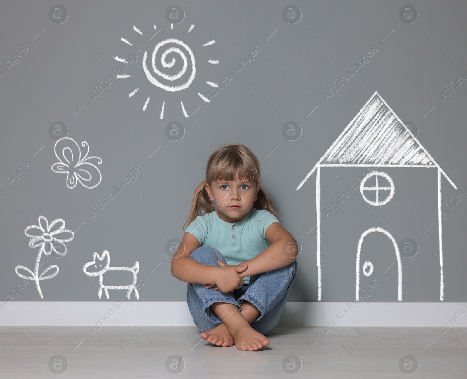 Orphanage. Sad little girl on floor near grey wall with different drawings Image of Orphanage. Sad little girl on floor near grey wall with different drawings