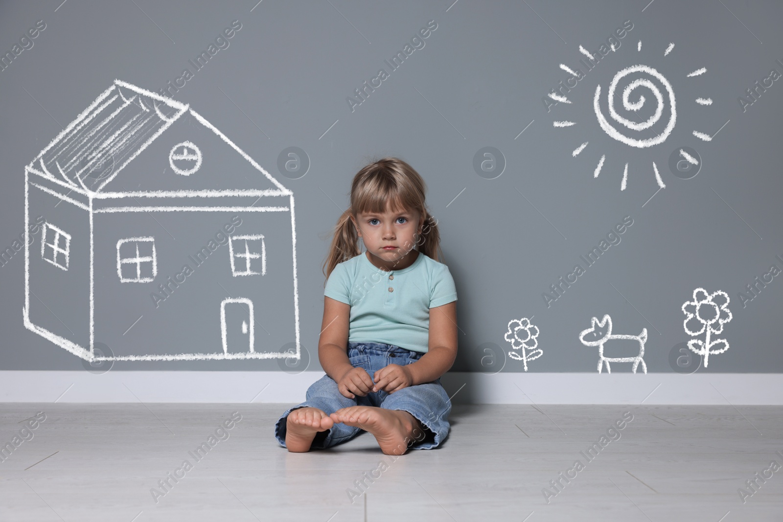 Orphanage. Sad little girl on floor near grey wall with drawings of house, dog, sun and flowers Image of Orphanage. Sad little girl on floor near grey wall with drawings of house, dog, sun and flowers