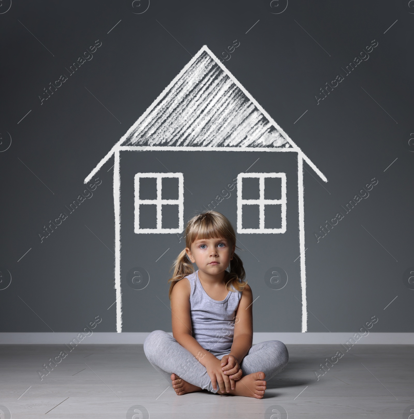 Image of Orphanage. Sad little girl on floor near grey wall with drawing of house